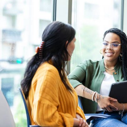 The young adult female guidance counselor listens carefully to the young adult female student.