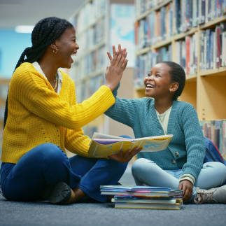 Library, girl and teacher high five for education goal, learning and celebration for storytelling. Educator, black woman and kid on floor for fun, fantasy stories and language development or relaxing